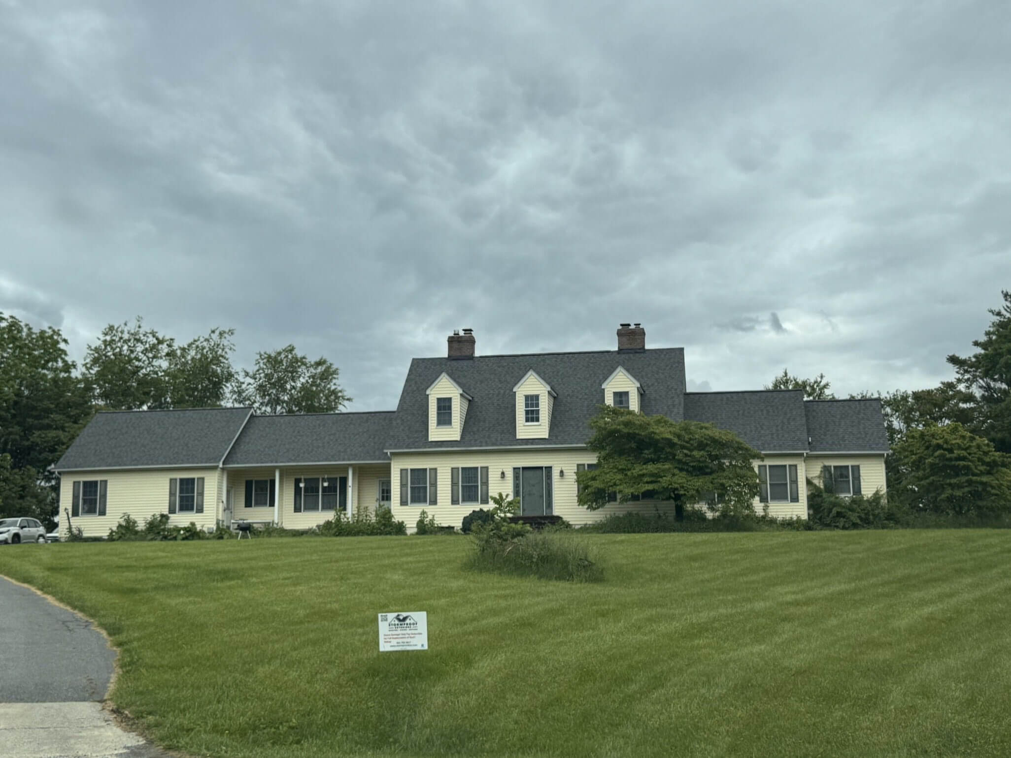 Yellow house with dark roof on lawn.