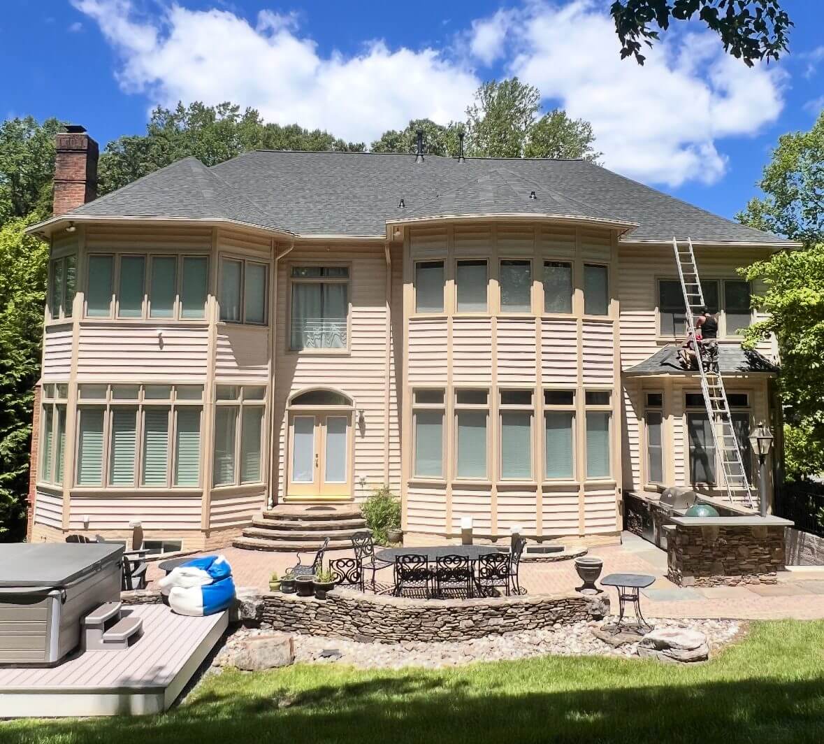 Large house with deck and surrounding trees.