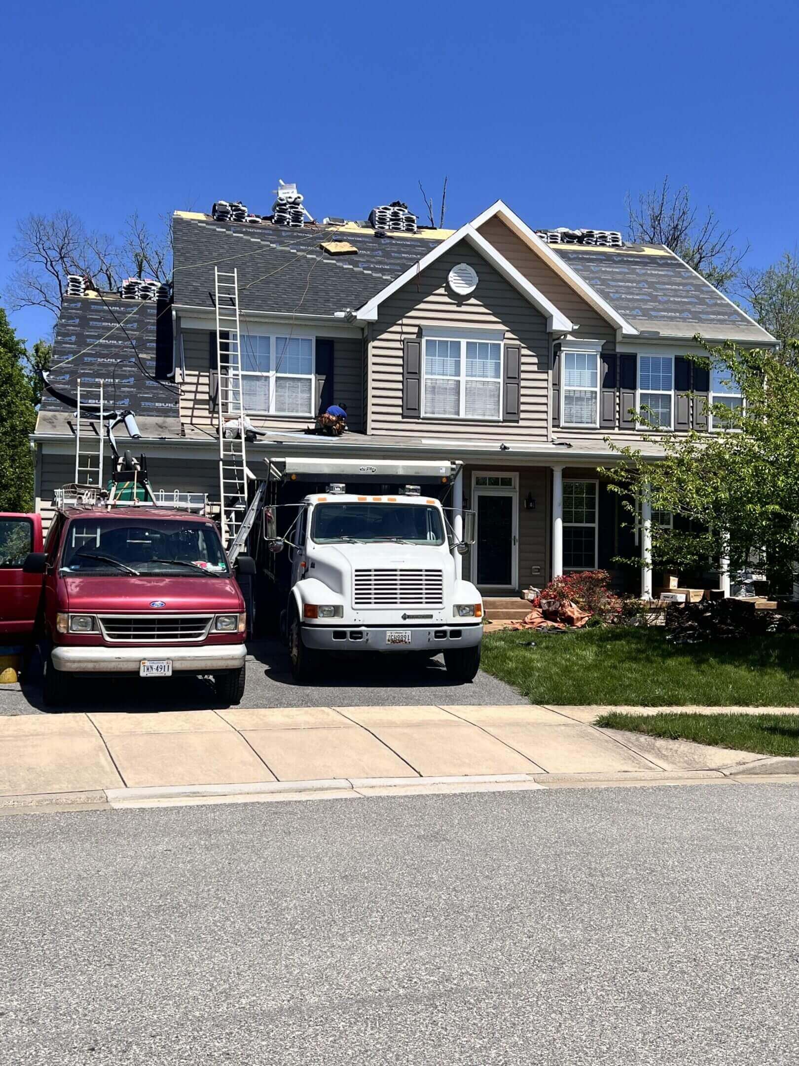 House under roof repair with vehicles parked.