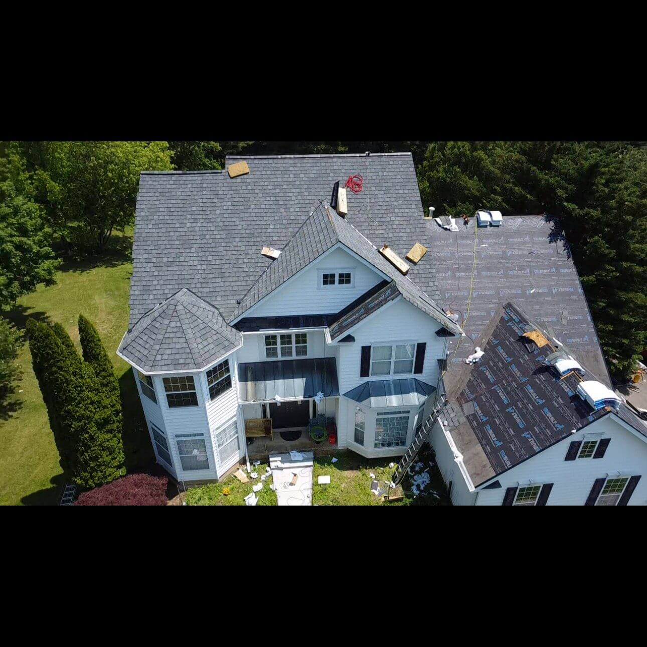 House with partially installed new roof shingles.